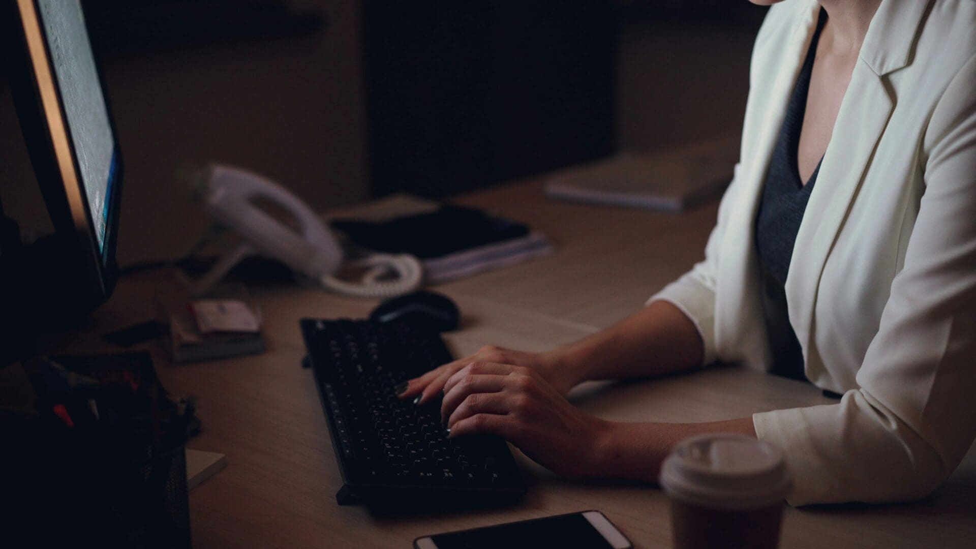 Professional typing late at night at a desk, representing the stress and fatigue addressed in virtual burnout therapy.