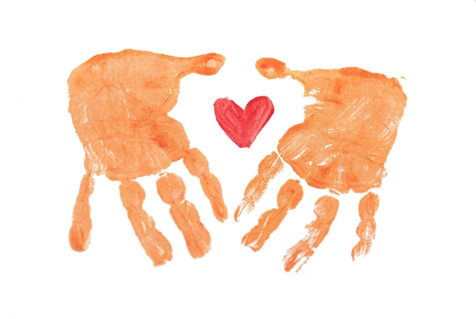 Two painted handprints with a heart between them, representing care, connection, and family support in co-parenting therapy.
