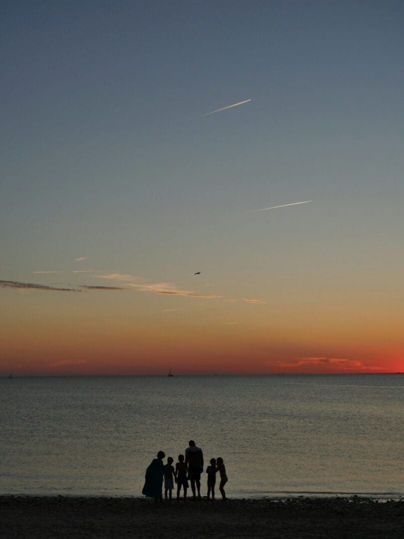 Family standing together on a beach at sunset, reflecting connection and shared support in co-parenting therapy.