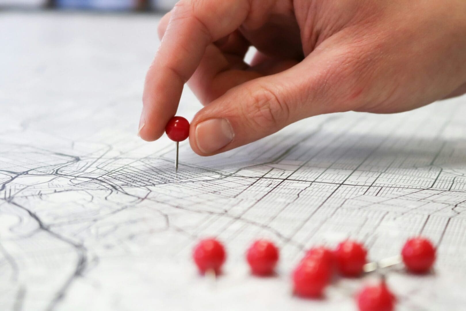 Hand placing a red pin on a map, symbolizing focus, insight, and progress in emotion-focused therapy in Spokane, Wa.