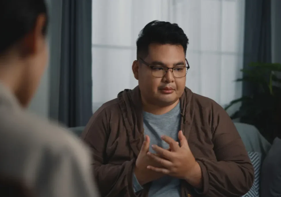Man in glasses speaking earnestly during a conversation.