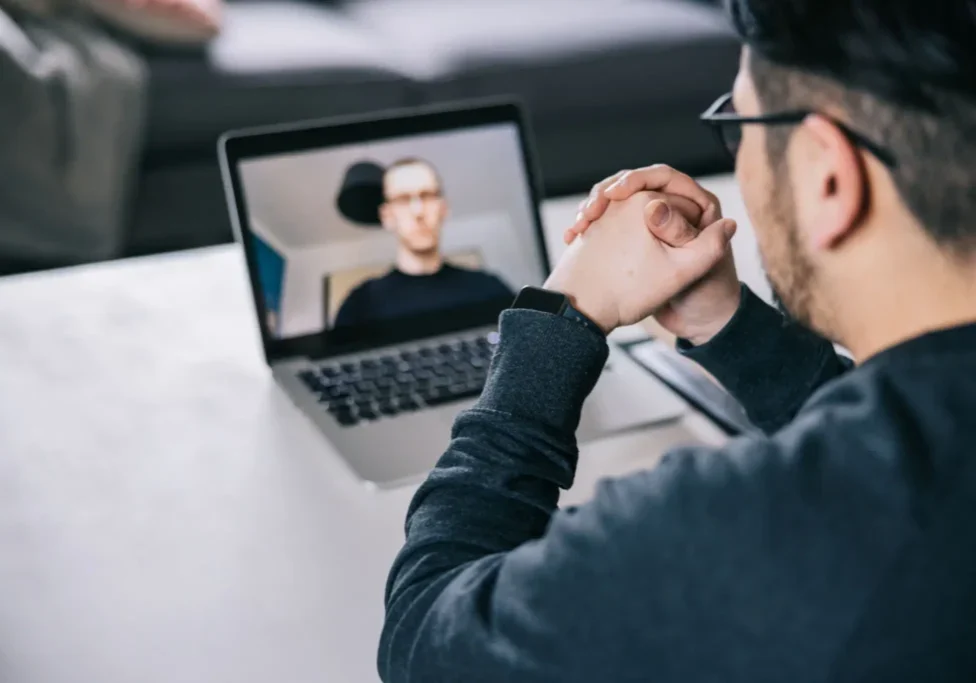Man in glasses video conferencing on laptop indoors.