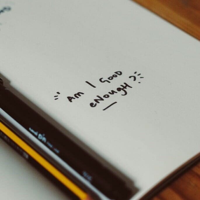 Notebook page with the handwritten question “Am I good enough?” representing the self-doubt explored in imposter syndrome therapy in Seattle.